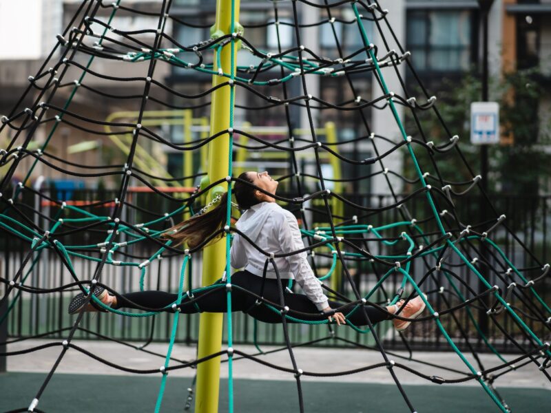 Young woman having fun on the rope pyramid on the playground